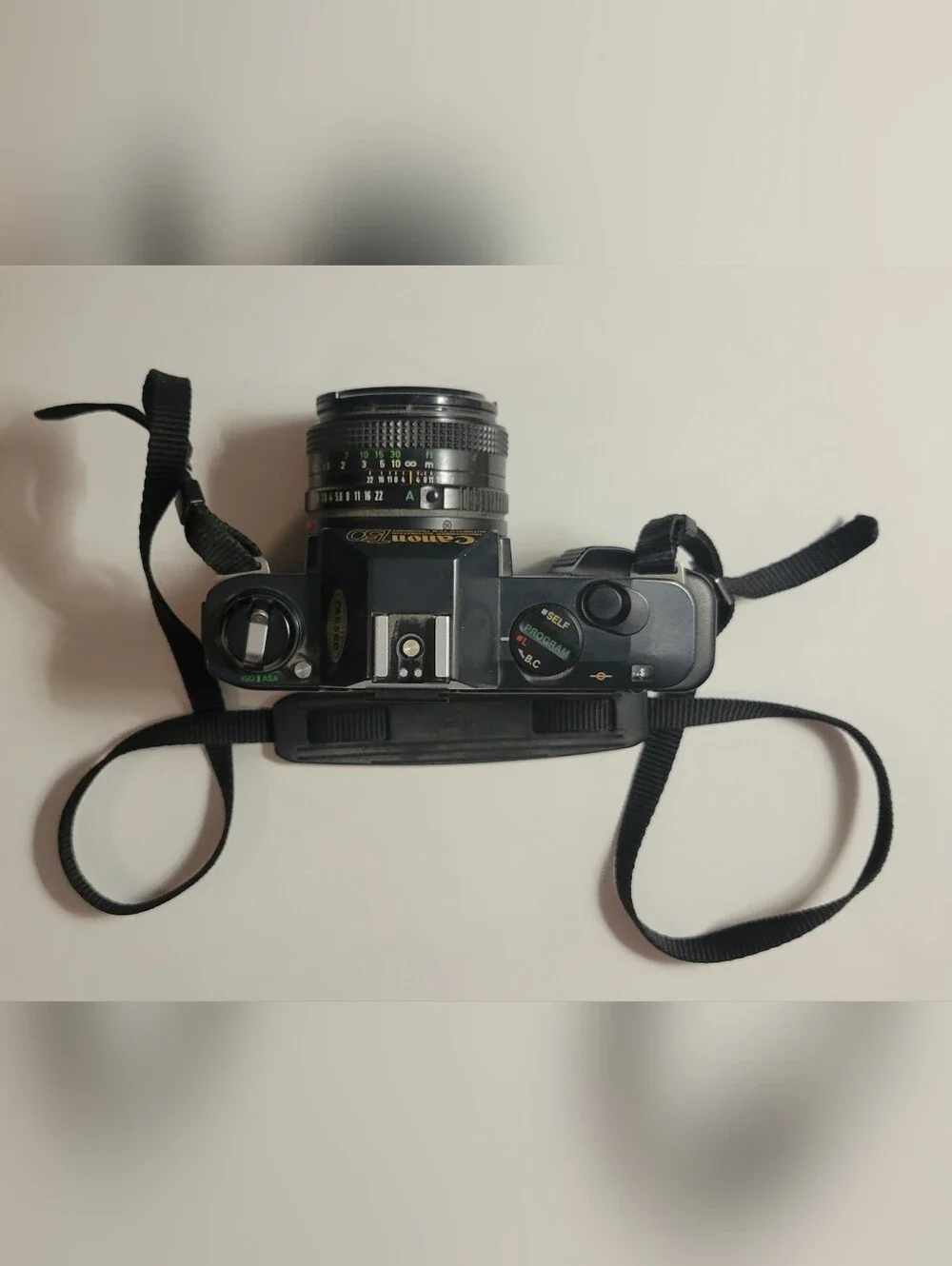 Canon black film camera with 50mm FD f/1.8 lens and neck strap